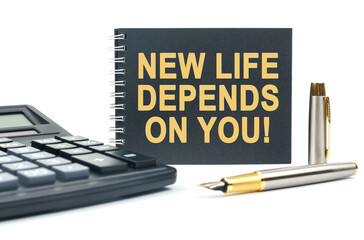On a white background, there is a calculator, a pen and a black notebook with the inscription - NEW LIFE DEPENDS ON YOU