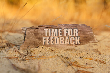 In the sand against the background of yellow grass there is a sign with the inscription - TIME FOR FEEDBACK