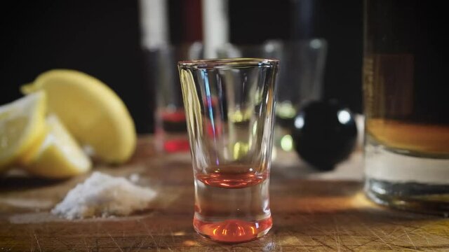Trago de tequila reposado con rodaja de lim&oacute;n con el fondo desenfocado
