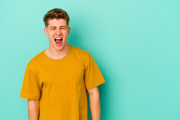 Obraz premium Young caucasian man isolated on blue background shouting very angry, rage concept, frustrated.