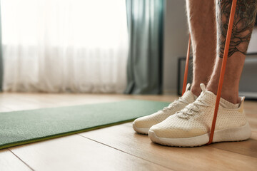 Male legs with a tattoo standing on floor near mat