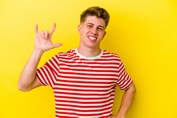 Fototapeta premium Young caucasian man isolated on yellow background showing rock gesture with fingers