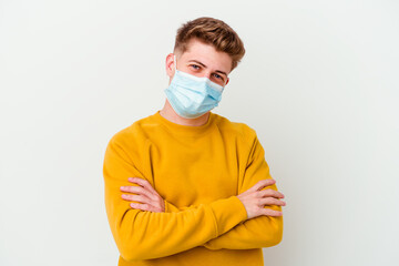Young man wearing a mask for coronavirus isolated on white background who feels confident, crossing arms with determination.