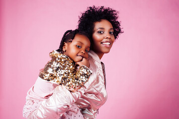 young pretty african-american mother with little cute daughter hugging, happy smiling on pink...