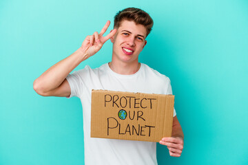 Young caucasian man holding a protect our planet placard isolated on blue background