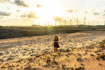 Menina se diverte com exercícios em dunas de areia ao por do sol