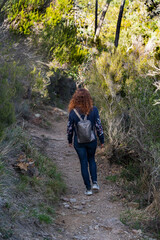 Naklejka premium Young woman with a backpack goes hiking in the mountains of Theoule-sur-Mer city on the Mediterranean coast of France.