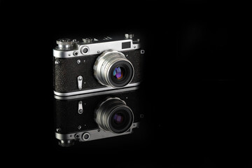 The rare old rangefinder film camera on black glass background.