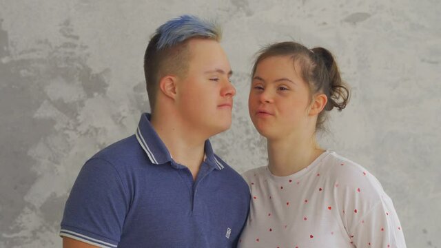 Cheerful teenage couple with Down Syndrome kiss each other