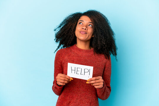 Young african american curly woman holding a help placard dreaming of achieving goals and purposes