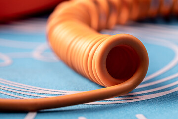 Twisted orange telephone cord on a blue background. Closeup photo with a low depth of field.