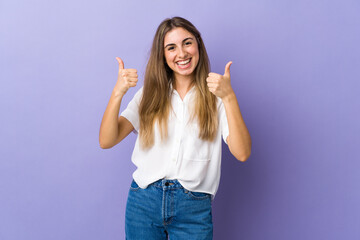 Young woman over isolated purple background with thumbs up gesture and smiling