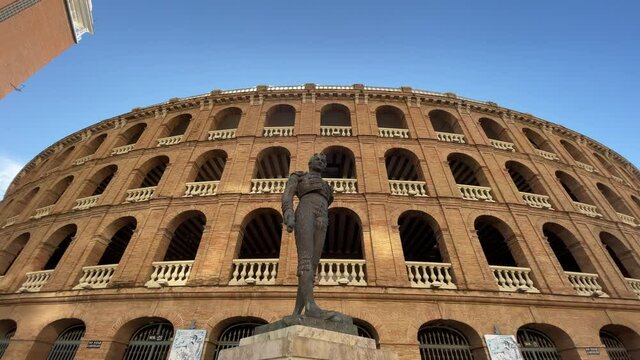 VALENCIA, SPAIN - FEBRUARY 13, 2021: Walking towards Plaza de Toros de Valencia with low angle shot of statue of Toreador Manolo Montoliu