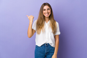 Fototapeta na wymiar Young woman over isolated purple background pointing to the side to present a product