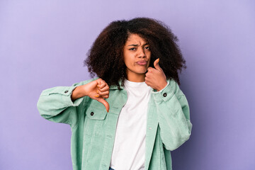 Young african american curly woman isolated on purple background showing thumbs up and thumbs down, difficult choose concept