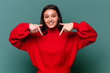 Fototapeta premium Young Indian woman isolated on blue background points down with fingers, positive feeling.