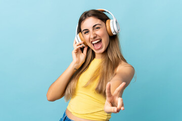 Young woman over isolated blue background listening music and singing