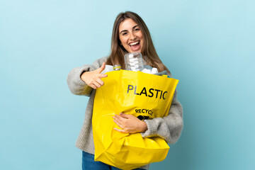 holding a bag full of plastic bottles to recycle over isolated blue points finger at you