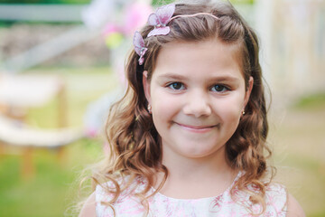 Portrait of a beautiful girl with dark blond hair on the background of a swing decorated with flowers