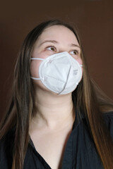 masked girl with long hair, teenager, white medical mask, a protective respirator with a high degree of protection class FFP2, COVID-19 coronavirus in europe, flu, infection