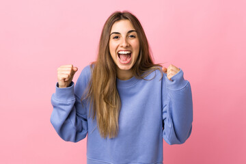 Young woman over isolated pink background celebrating a victory in winner position