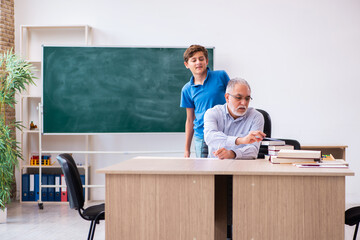 Old male teacher and schoolboy in the classroom