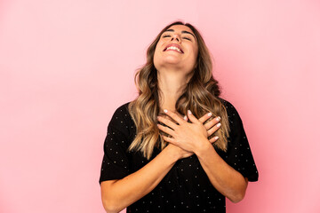 Young caucasian woman isolated laughing keeping hands on heart, concept of happiness.