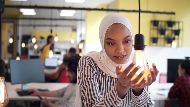 Happy muslim woman holding and showing a glowing light bulb