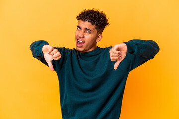 Young african american curly man isolated on purple showing thumb down and expressing dislike.