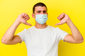 Young caucasian man wearing a protection for coronavirus isolated on yellow background feels proud and self confident, example to follow.