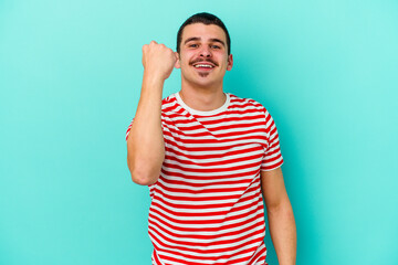 Young caucasian man isolated on blue background cheering carefree and excited. Victory concept.