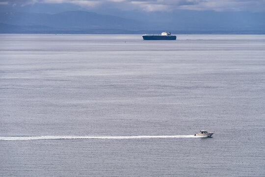 Small Craft Leaves Wake In Foreground, In Background A Container Ship Heading Into Puget Sound Port