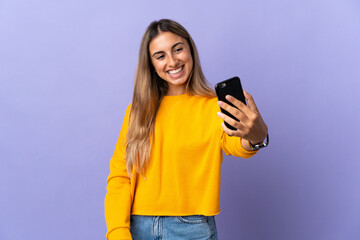 Young hispanic woman over isolated purple background making a selfie