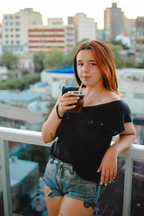 jovencita tomando mate en el balcon de su casa 