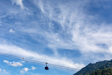Fototapeta na wymiar Blue cable car above the clouds against the sky