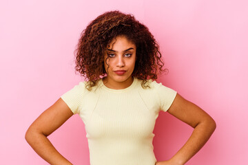 Young african american woman isolated on pink background blows cheeks, has tired expression. Facial...