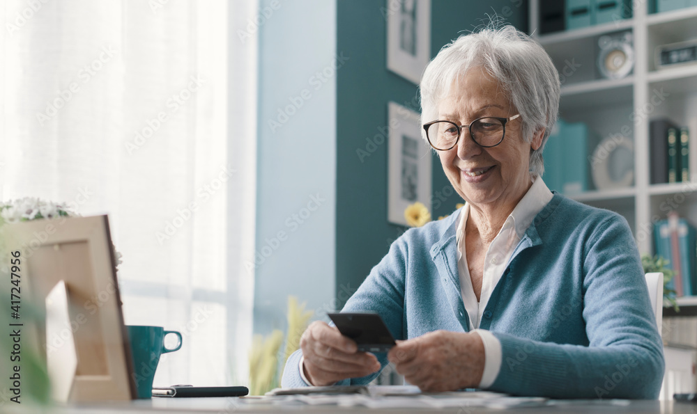 Wall mural happy senior lady going through old pictures