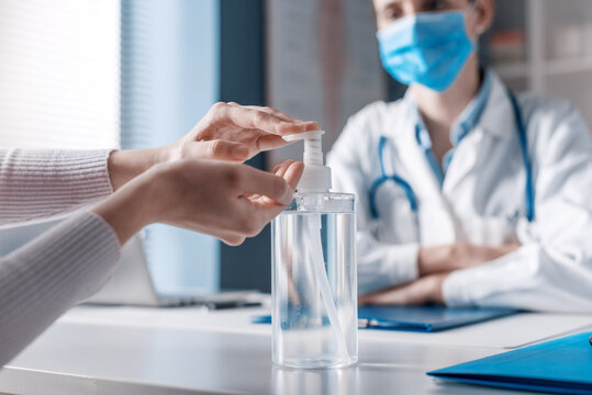 Patient sanitizing hands in the doctor's office - Powered by Adobe
