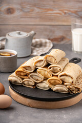 Fototapeta na wymiar Thin pancakes stuffed with cottage cheese on iron pan. Breakfast table