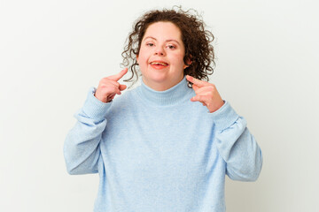 Woman with Down syndrome isolated smiles, pointing fingers at mouth.