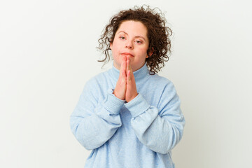 Woman with Down syndrome isolated holding hands in pray near mouth, feels confident.