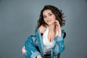 portrait of a dark-haired beautiful girl model with a gorgeous smile in white underwear and a denim jacket