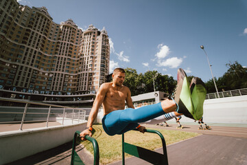 Fototapeta premium Strong man doing exercises on uneven bars in outdoor street gym.