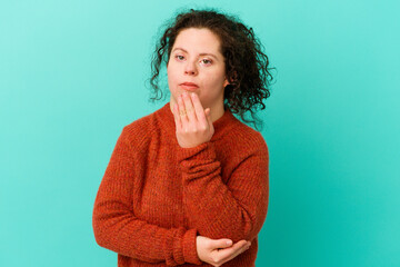 Woman with Down syndrome isolated yawning showing a tired gesture covering mouth with hand.