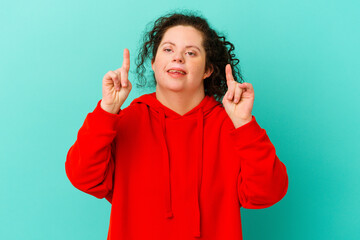 Woman with Down syndrome isolated indicates with both fore fingers up showing a blank space.