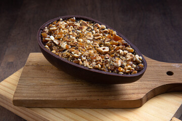 Stuffed hazelnut and chocolate easter egg on a wooden stand on a wooden table.