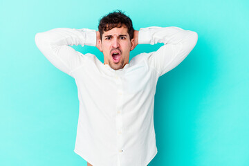 Young caucasian man isolated on blue background screaming with rage.