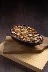 Stuffed hazelnut and chocolate easter egg on a wooden stand on a wooden table.