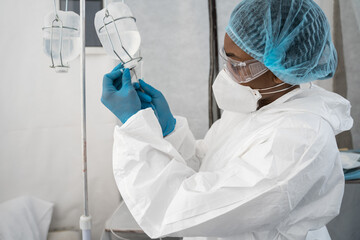 Nurse wearing protective equipment preparing dropper for her patient