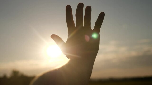 girl stretches out her hand in the sun. faith in god dream a religion sunlight concept. hand sun in the close-up silhouette dream of happiness